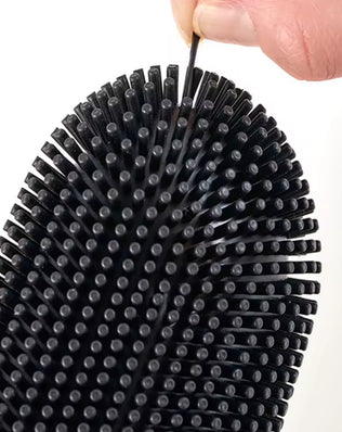 Stainless steel base toilet brush from Problems Solved standing next to a toilet for cleaning and sanitation.